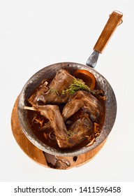 Portions Of Roasted Wild Rabbit Venison In Gravy Seasoned With Spices, Herbs, Mushrooms And Garnished With Orange Zest Viewed From Overhead On A Wooden Board Isolated On White