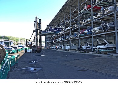 Portland Dorset England.  Large Portable Hoist Removing Pleasure Craft From A Dry Stacked Boat Storage Unit. Unit Has Five Tiers. Large Unit With Open Front. Boats  Stored On Racks.