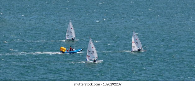 Portland Harbour, United Kingdom - July 2, 2020: High Angle Aerial Panoramic Shot Of The Laser Class Sailing Racing Dinghies And A Rescue Boat In Portland Harbour.