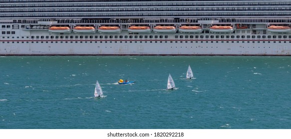 Portland Harbour, United Kingdom - July 2, 2020: High Angle Aerial Panoramic Shot Of The Laser Class Sailing Racing Dinghies And A Rescue Boat Sailing By A Huge Cruise Ship In Portland Harbour.