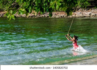 Portland, Jamaica - May 11 2019: Young Black Pre Teen/preteen Jamaican Girl Child Playing On Swing Tied With Rope To Tree On River/beach. Fun Traditional Tropical Caribbean Island Summer Setting.