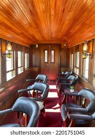 Portland, ME, USA, 9.1.22 - The Inside Of An Old, Refurbished Train Car. There Are Leather Seats, Wooden Paneling, Antique Lamps, And Red Carpeting.