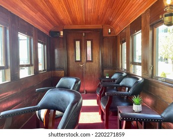 Portland, ME, USA, 9.1.22 - The Inside Of An Old, Refurbished Train Car. There Are Leather Seats, Wooden Paneling, Antique Lamps, And Red Carpeting.