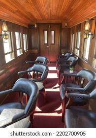 Portland, ME, USA, 9.1.22 - The Inside Of An Old, Refurbished Train Car. There Are Leather Seats, Wooden Paneling, Antique Lamps, And Red Carpeting.