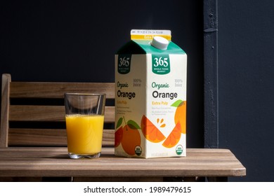 Portland, OR, USA - Apr 28, 2021: Closeup Of A Carton Of 365 By Whole Foods Market Branded 100 Percent Organic Orange Juice With Extra Pulp On A Wooden Outdoor Dining Table.