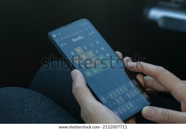 Portland, OR, USA - Feb 11, 2022: A woman plays\
the WORDLE game on the New York Times website from her Google\
smartphone in a car. WORDLE, the viral word game, has moved to the\
New York Times\
website.