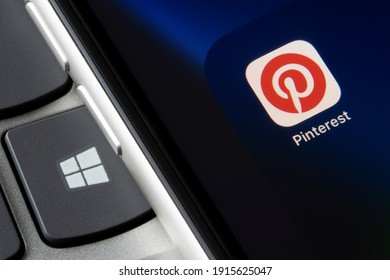 Portland, OR, USA - Feb 12, 2021: Pinterest App Icon Is Seen On An IPhone Beside The Microsoft Windows Logo Key On A Laptop Computer. Microsoft Has Been Approaching Pinterest About A Takeover.