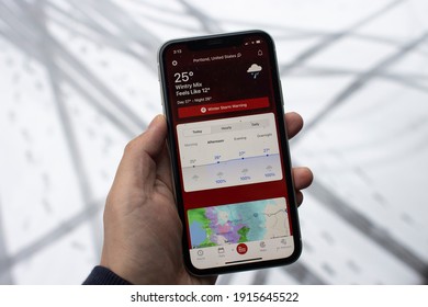 Portland, OR, USA - Feb 12, 2021: A Man Checks The Weather Update In Portland, Oregon, Using The Weather Channel App From His Phone. A Winter Storm Warning In Portland Metro Area Has Just Been Issued.