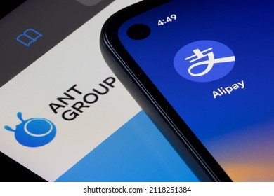 Portland, OR, USA - Feb 4, 2022: Alipay app icon is seen on a smartphone on top of an iPad screen showing the homepage of Ant Group. The group owns China's largest digital payment platform Alipay.