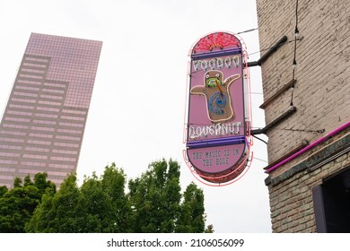 Portland, OR, USA - July 31 2022: Voodoo Doughnut Sign With A U.S. Bancorp Tower (Big Pink) In The Background. The Sign Reads 