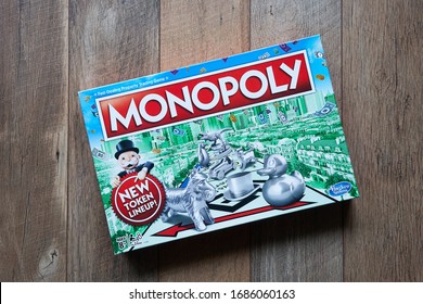 Portland, OR, USA - Mar 28, 2020: Top view of Monopoly board game box isolated on a wooden flooring background. The classic fast-dealing property trading board game is currently published by Hasbro.
