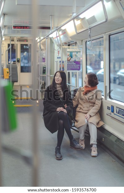 Portland, Oregon - Dec 15, 2019 : Happy asian\
elderly mother and adult daughter travel together riding Portland\
Streetcar