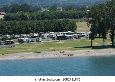 Portland, USA 07 16 2021: Landscape and shoreline with caravan cars and camping van  parked in riverside of Columbia river on the way from Portland, Oregon, to Pacific ocean. In background green trees