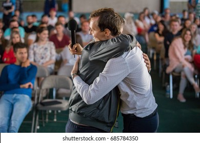 PORTLAND, USA - JULY 20 2017: Two men are hugging on stage in front of the student class