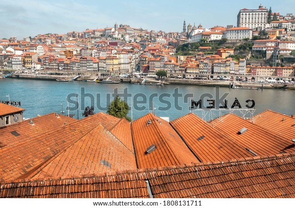 PORTO, PORTUGAL: Cityscape\
with red tile roofs of the old wineries and river Douro under blue\
sky on 22 May, 2019. Portuguese language has 250 million total\
speakers