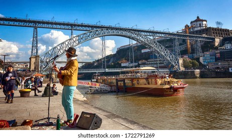Porto / Portugal - January 25 2020: A Street Musician At The Waterfront By The Ponte De Dom Luís I Bridge.