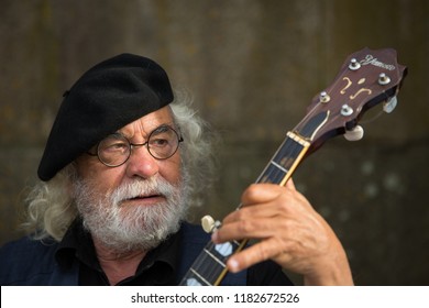 Porto, Portugal - June 13 2018 - Old Man In A Black Beret And Beard Entertaining Tourists By Playing A Portuguese Banjo Outside The Gothic Se Cathedral In The Northern District Of Porto City, Portugal