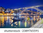 Porto, Portugal old town skyline on the Douro River with rabelo boats at night.