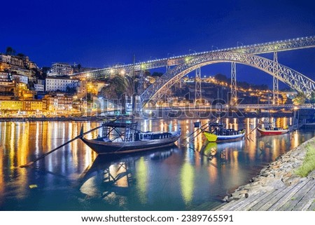 Porto, Portugal old town skyline on the Douro River with rabelo boats at night.