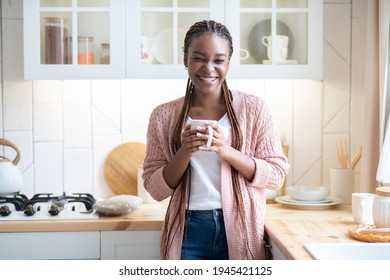 Portraif Of Cheerful Black Woman Enjoying Morning Coffee In Kitchen, Happy Black Female With Dental Braces And Braids Holding Cup With Caffeine Drink And Smiling At Camera, Relaxing At Home - Powered by Shutterstock