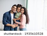 Portraif Of Happy Arabic Parents Posing With Their Little Daughter At Home