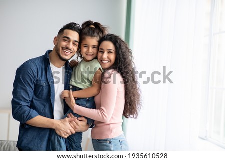 Portraif Of Happy Arabic Parents Posing With Their Little Daughter At Home