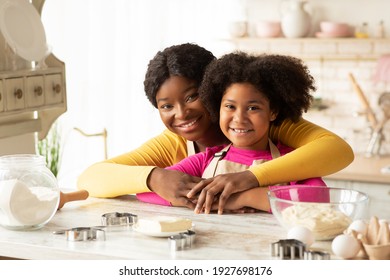 Portraif Of Loving Black Family Mom And Daughter In Aprons Posing At Table In Kitchen While Baking Together, African American Mother And Her Child Enjoying Cooking Homemade Food, Free Space