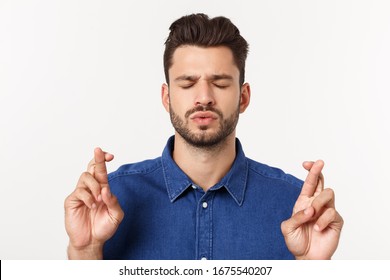 A Portrair Of A Young Man With Crossed Fingers And Closed Eyes Praying For Risky Business.