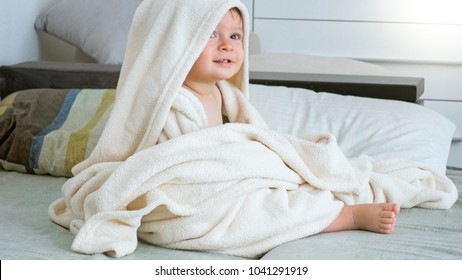 Portrait of 1 year old toddler boy sitting under big towel after having bath - Shutterstock ID 1041291919