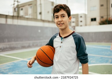 Portrait Of 12 Year Old Boy With Basketball. Teenager Training Basketball Outdoors.