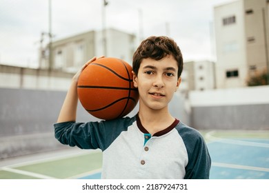 Portrait Of 12 Year Old Boy With Basketball. Teenager Training Basketball Outdoors.