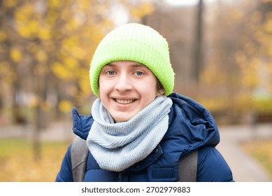 Portrait of a 13-year-old boy in a jacket with a backpack in the autumn park