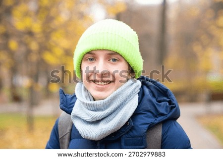 Portrait of a 13-year-old boy in a jacket with a backpack in the autumn park