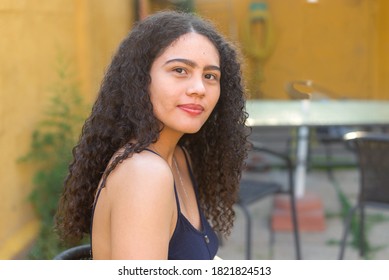 Portrait of 19 year old Hispanic woman with curly hair, looking