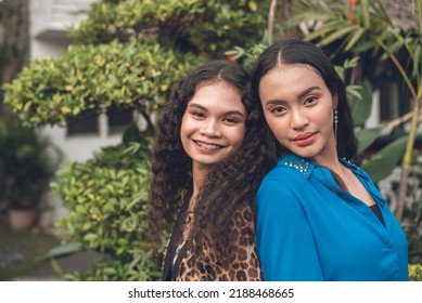 Portrait Of 2 Attractive And Lovely Asian Women Leaning On Each Other Back To Back. Two Close Friends At The Garden.