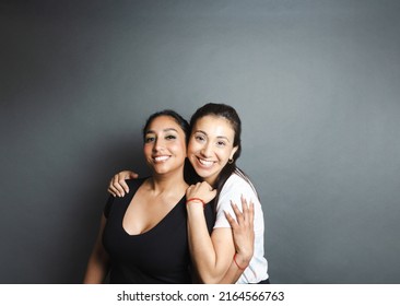 portrait of 2 diverse women smiling embracing looking at the camera