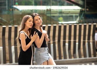 Portrait Of 20s And 40s Asian LGBTQ+ Lesbian Couple Hug Together And Smile Happy. Woman And Transgender Female Feels Fun To Walk Street Outdoor For Shopping