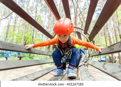 Portrait of 3 years old boy wearing helmet and climbing. Child in a wooden abstacle course in adventure playground - Powered by Shutterstock