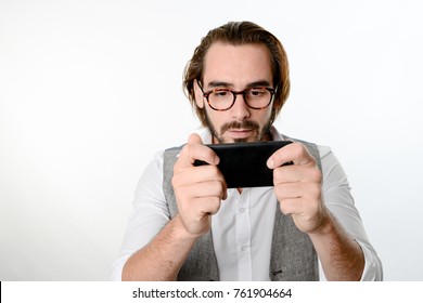 Portrait Of A 30 Years Old Nerd Geek Playing Game App On A Smartphone Isolated On White Background 