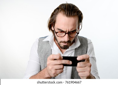 Portrait Of A 30 Years Old Nerd Geek Playing Game App On A Smartphone Isolated On White Background 