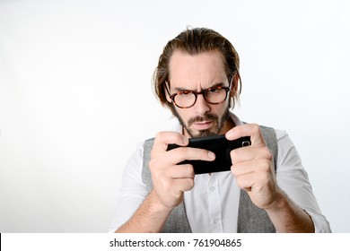 Portrait Of A 30 Years Old Nerd Geek Playing Game App On A Smartphone Isolated On White Background 