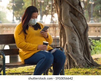 Portrait of 30-35 year old Asian woman with long black hair wearing an orange T-shirt. Sit on chair Happily and independently Along with cup of hot coffee In hand in garden ready In happy sunset time
