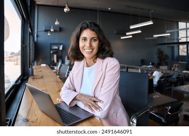 Portrait 30s latin hispanic business woman manager working on laptop computer in modern office. Smiling Indian young businesswoman professional entrepreneur using pc app at workplace looking at camera - Powered by Shutterstock