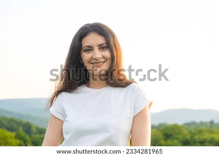Portrait of a 35-year-old European woman smiling while looking at the camera while walking in nature in a field