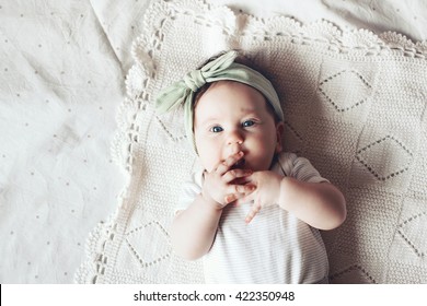 Portrait Of A 4 Month Cute Baby Girl Wearing Lace Flower Headband And Lying Down On A Crochet Blanket