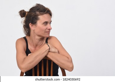 Portrait Of A 40 Year Old Woman Without Makeup On White Background, Sitting On A Chair And Looking At The Side