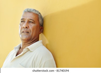 Portrait Of 50 Years Old Latin American Man Having Problems And Leaning On Yellow Wall. Horizontal Shape, Copy Space