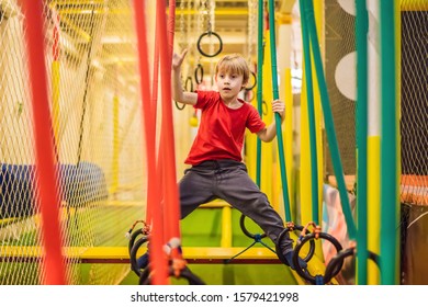 Portrait of 6 years old boy wearing helmet and climbing. Child in abstacle course in adventure playground - Powered by Shutterstock