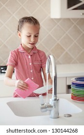 Portrait Of A 6 Years Old Girl Washing The Dishes At Home