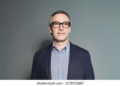 Portrait Of 60 Year Old Man In Glasses On Grey Background